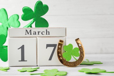 Photo of Composition with block calendar on white wooden table. St. Patrick's Day celebration