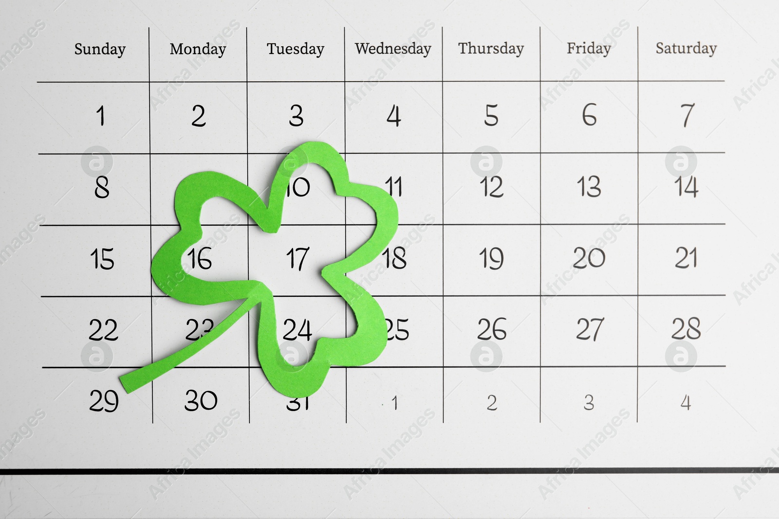 Photo of 17th March marked with paper clover leaf on calendar, top view. St. Patrick's Day celebration