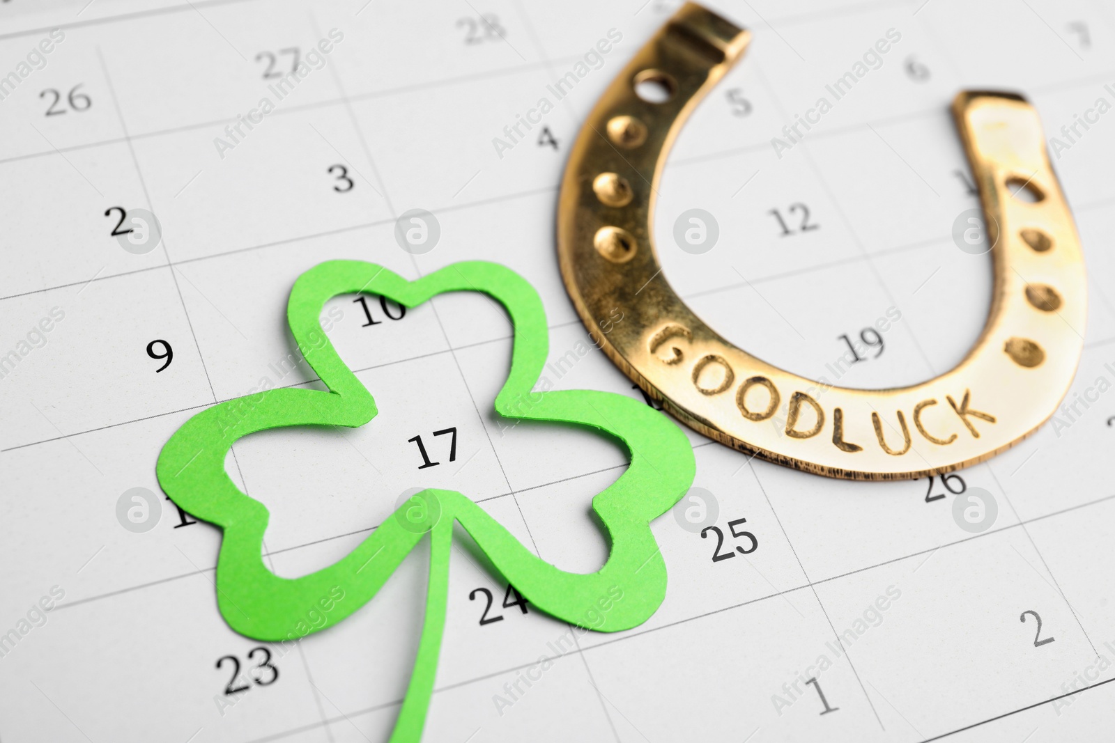 Photo of 17th March marked with paper clover leaf and golden horseshoe on calendar. St. Patrick's Day celebration