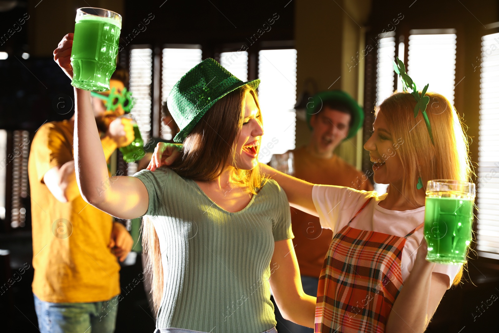 Photo of Young women with glasses of green beer in pub. St. Patrick's Day celebration