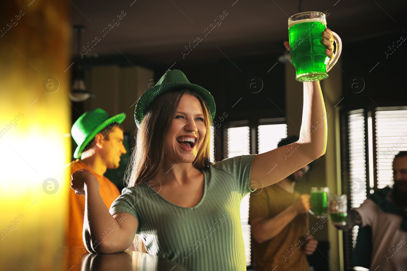 Photo of Young woman with glass of green beer in pub. St. Patrick's Day celebration