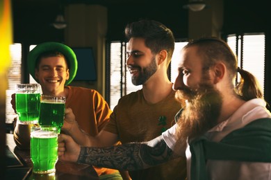 Photo of Group of friends toasting with green beer in pub. St. Patrick's Day celebration