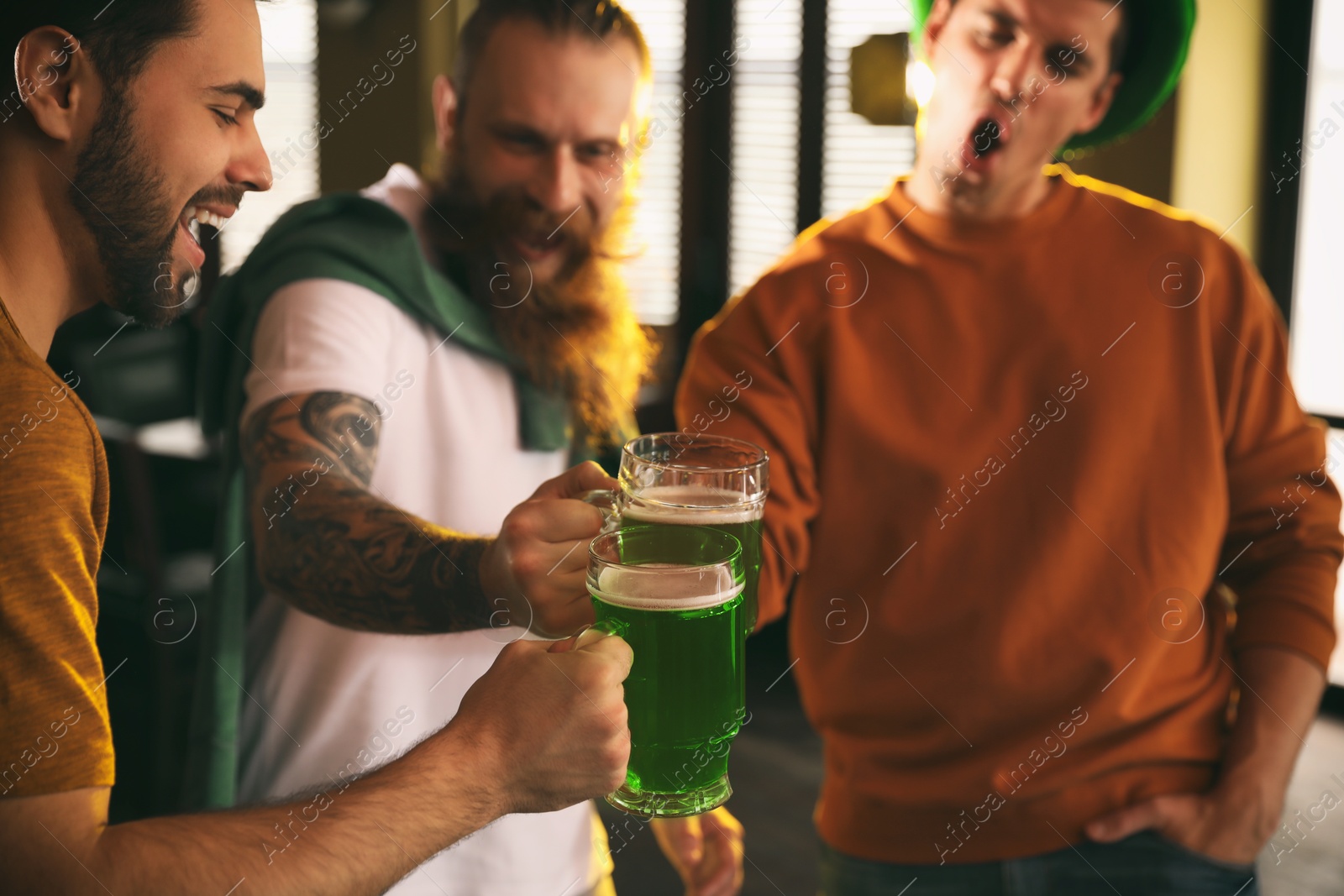 Photo of Group of friends toasting with green beer in pub. St. Patrick's Day celebration