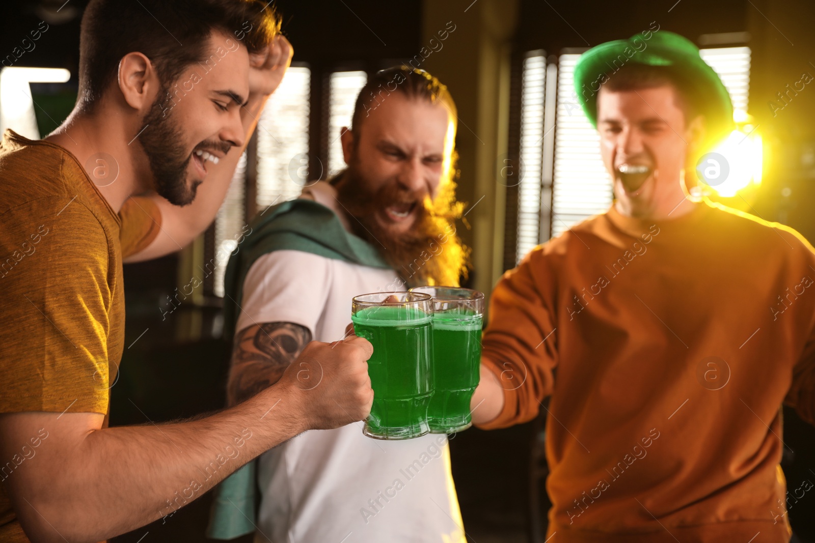 Photo of Group of friends toasting with green beer in pub. St. Patrick's Day celebration