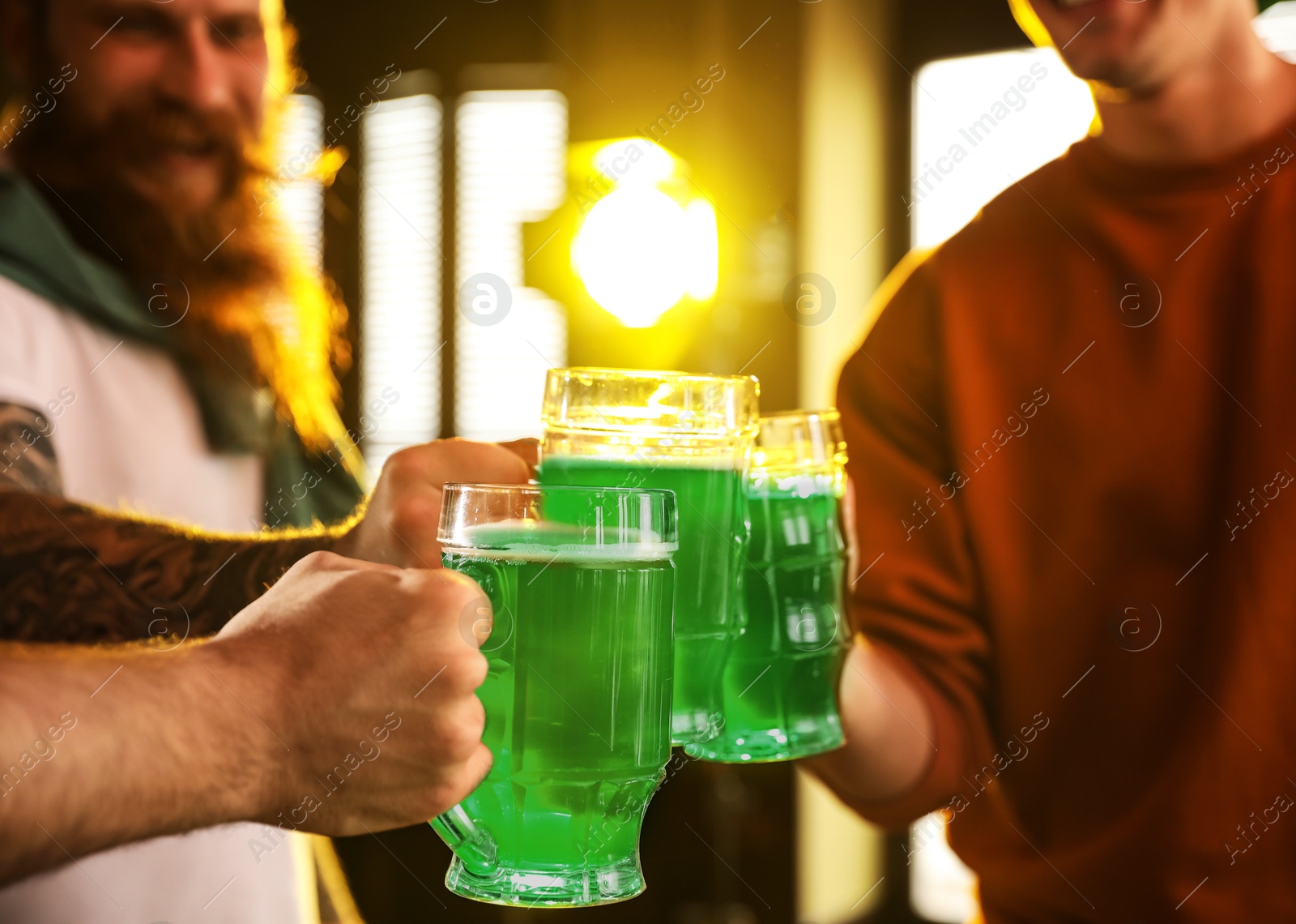 Photo of Group of friends toasting with green beer in pub, closeup. St. Patrick's Day celebration