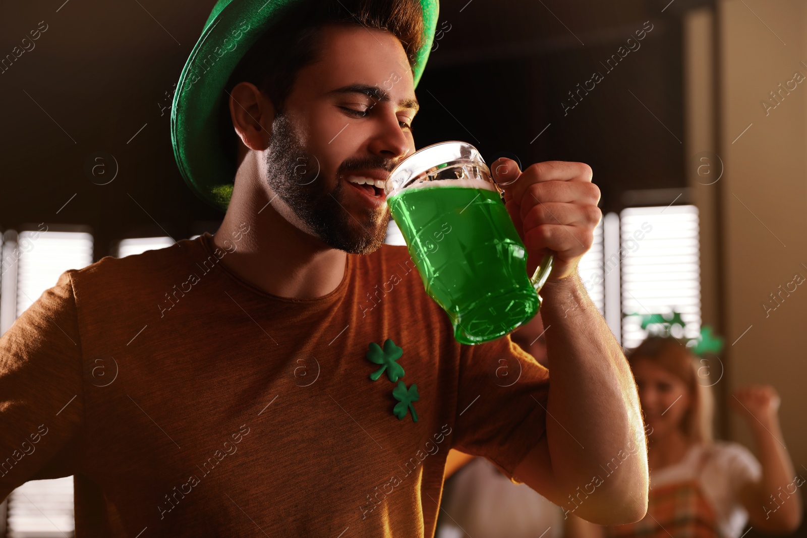 Photo of Young man drinking green beer in pub. St. Patrick's Day celebration