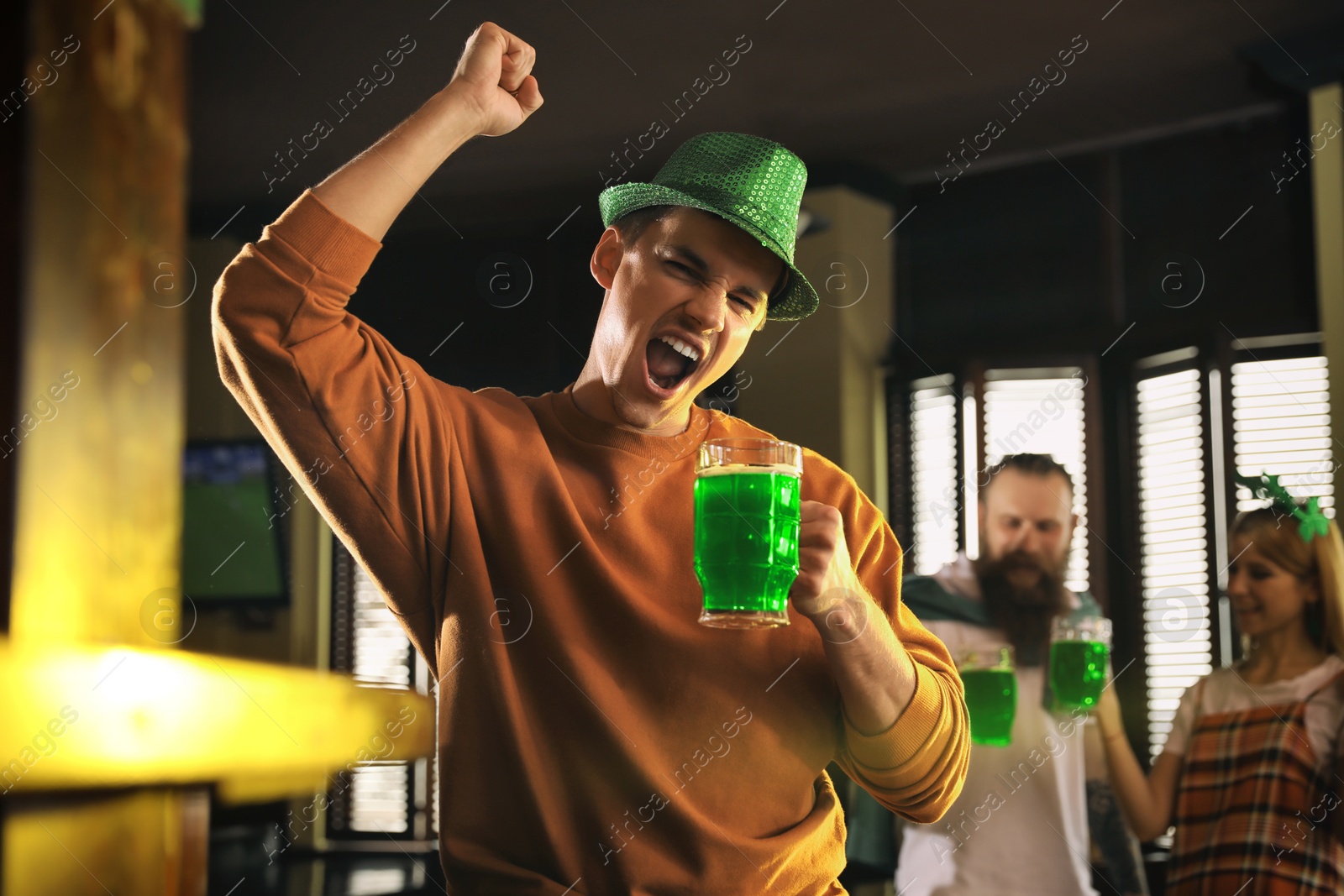 Photo of Emotional man with glass of green beer in pub. St. Patrick's Day celebration