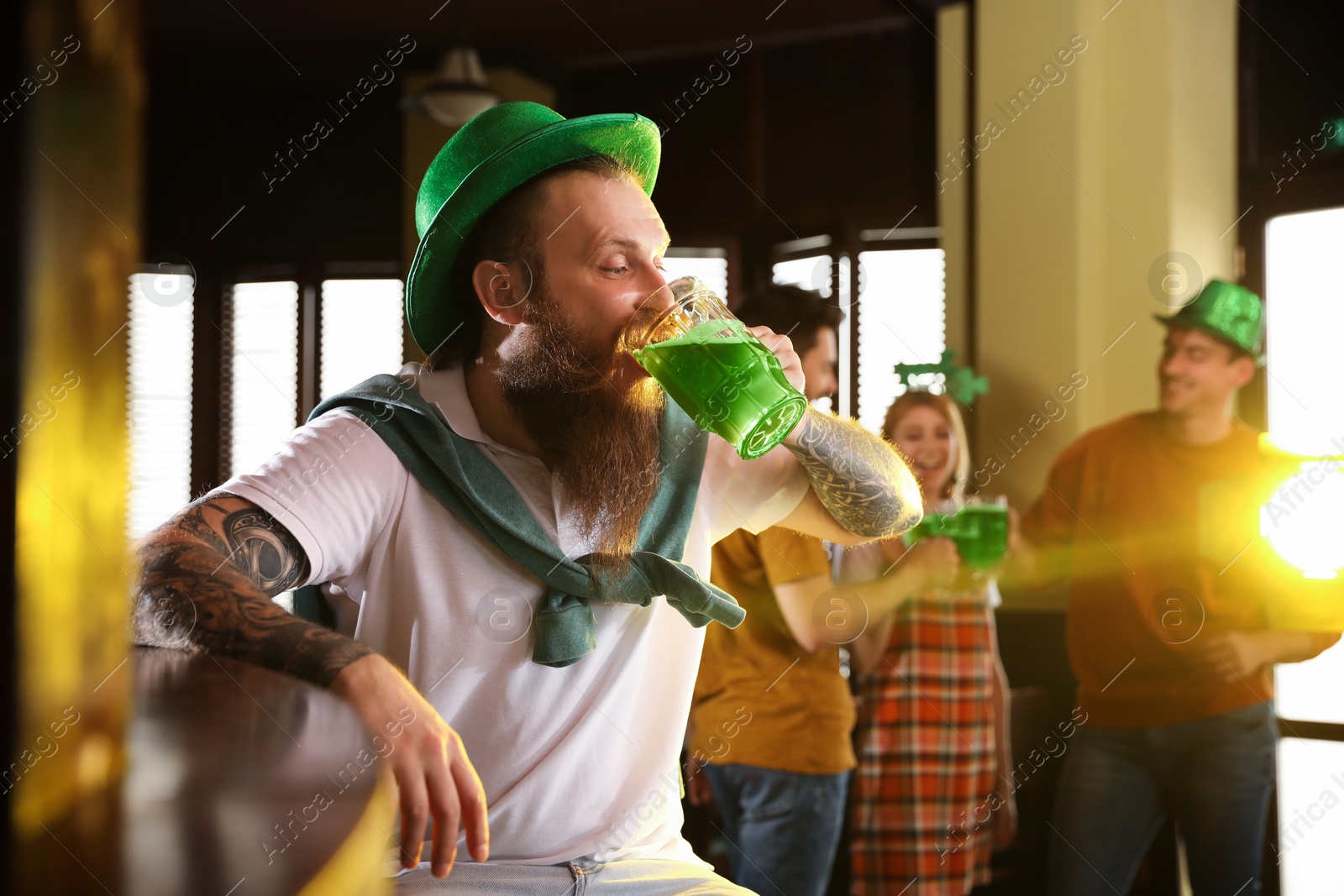 Photo of Man drinking green beer in pub. St. Patrick's Day celebration