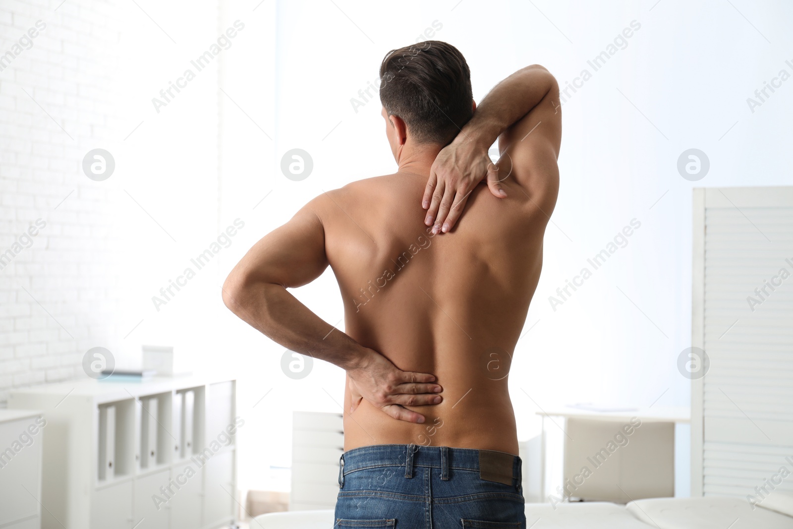 Photo of Man suffering from pain in back at clinic. Visiting orthopedist