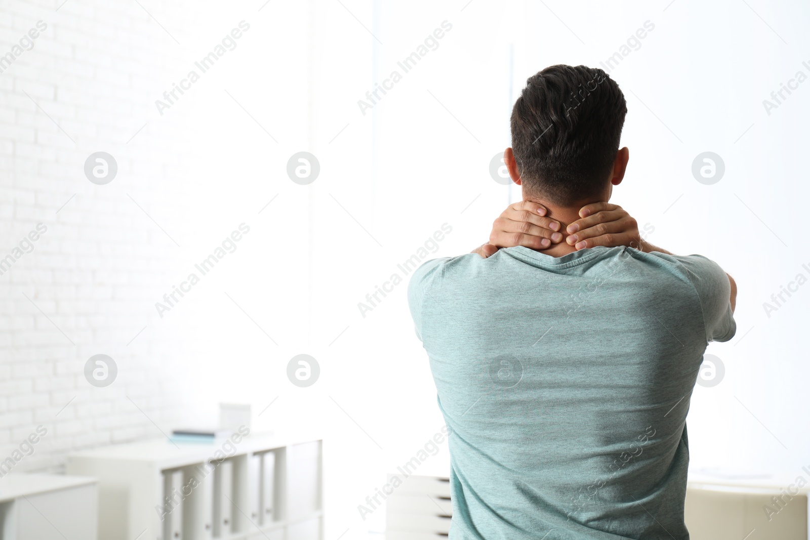 Photo of Man suffering from pain in neck at clinic, space for text. Visiting orthopedist