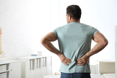 Photo of Man suffering from lower back pain at clinic. Visiting orthopedist