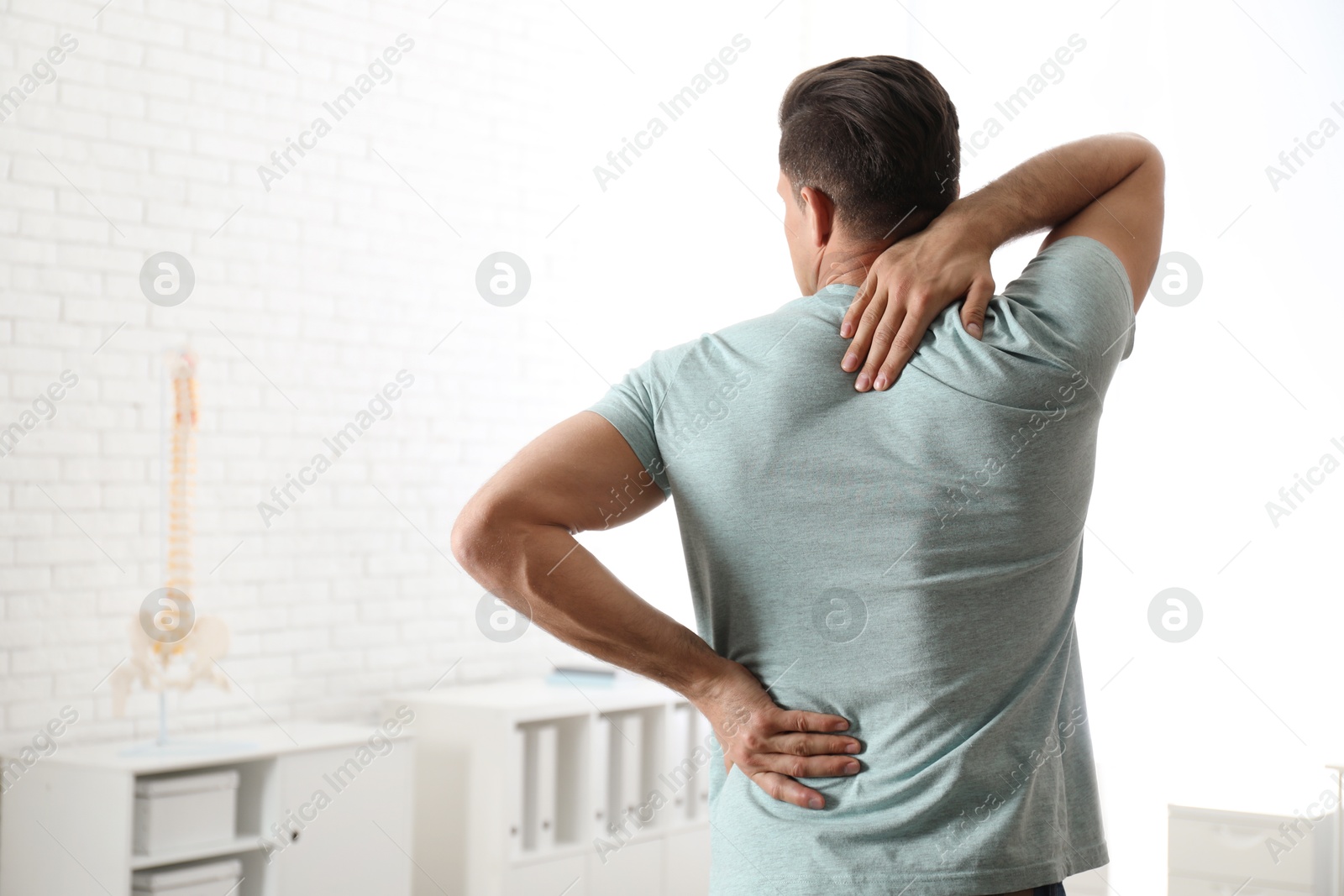 Photo of Man suffering from pain in back at clinic. Visiting orthopedist