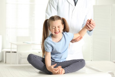 Photo of Professional orthopedist examining little patient's arm in clinic