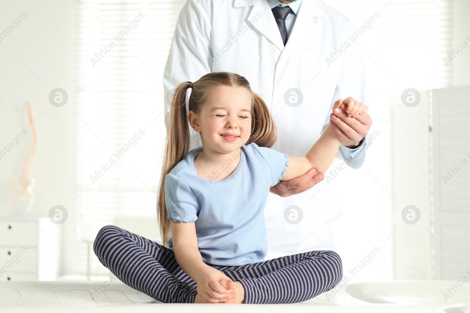 Photo of Professional orthopedist examining little patient's arm in clinic