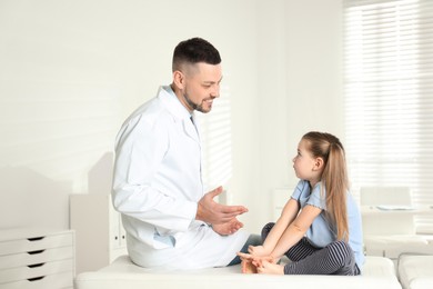 Photo of Professional orthopedist examining little girl in clinic