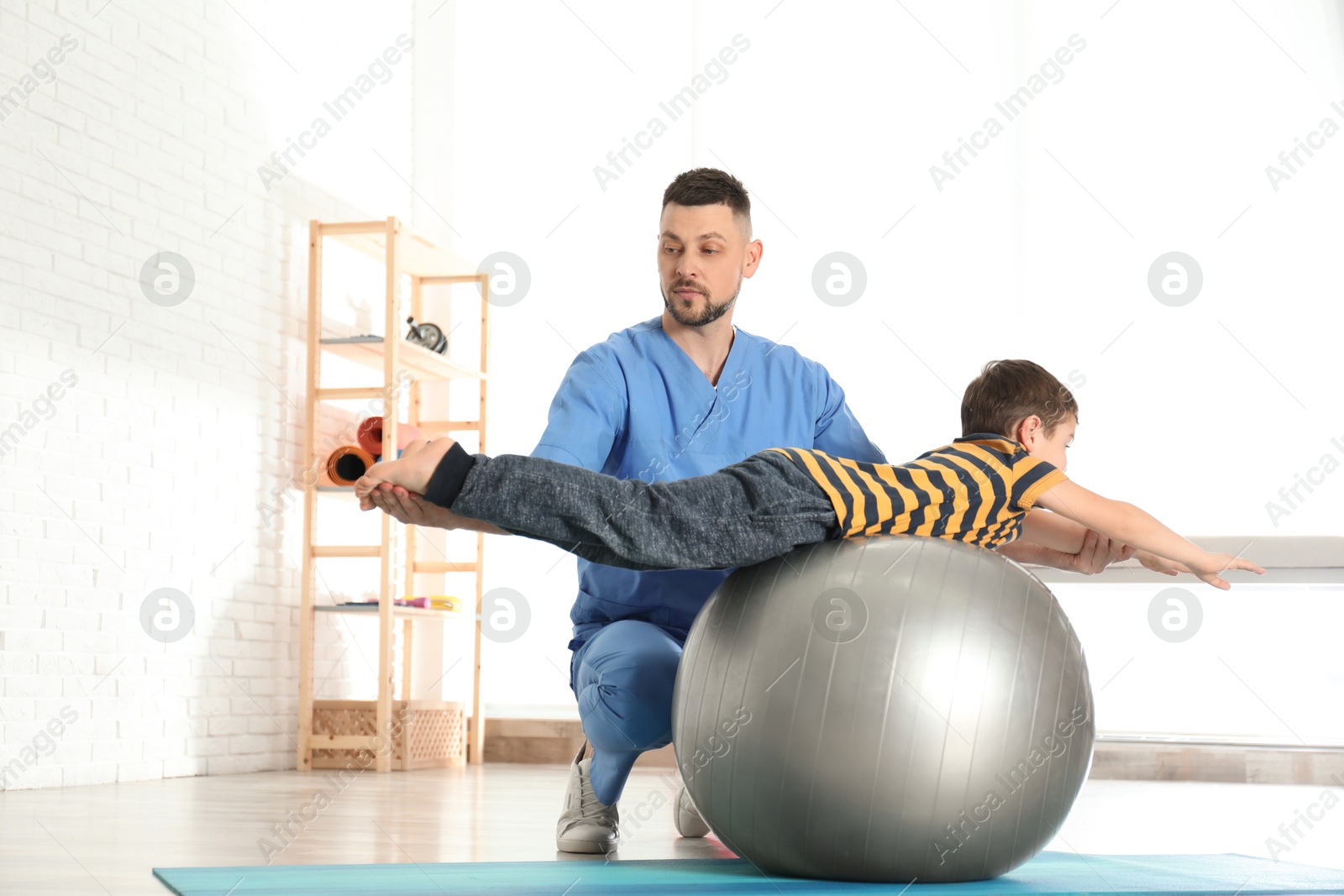 Photo of Orthopedist working with little boy in hospital gym