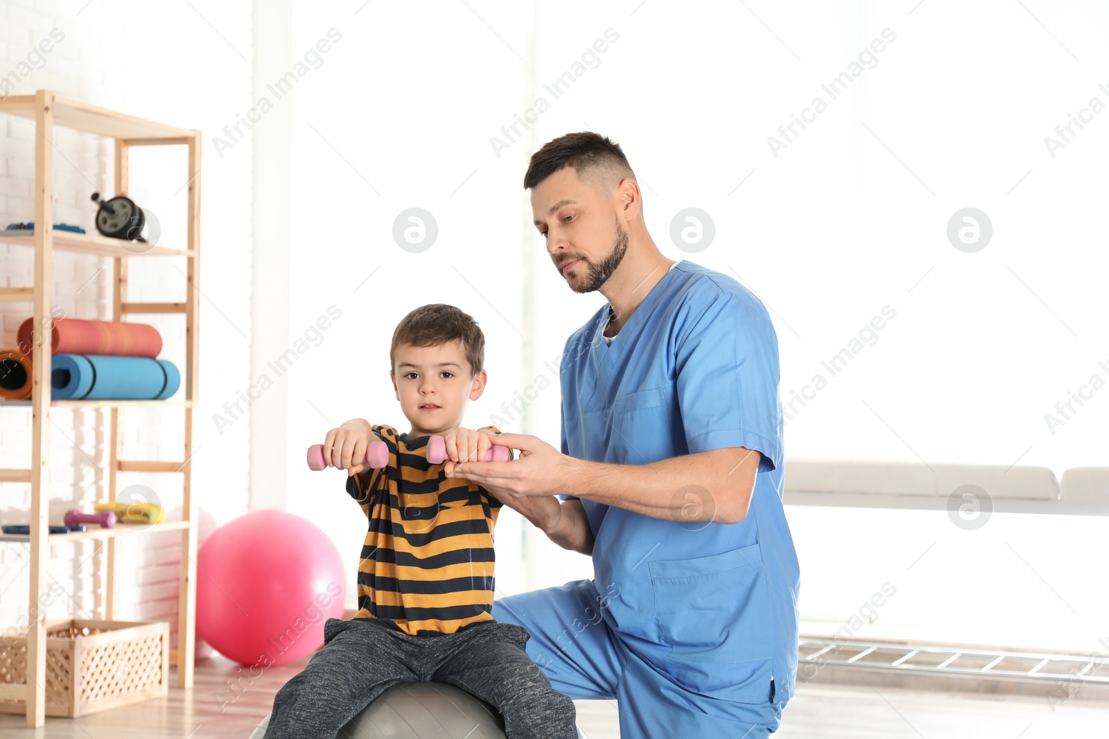 Photo of Orthopedist working with little boy in hospital gym