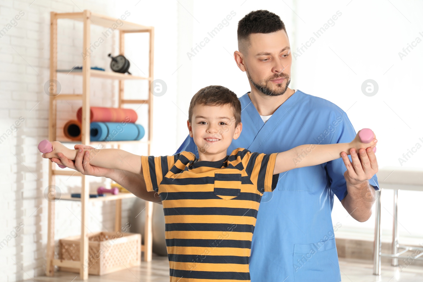 Photo of Orthopedist working with little boy in hospital gym