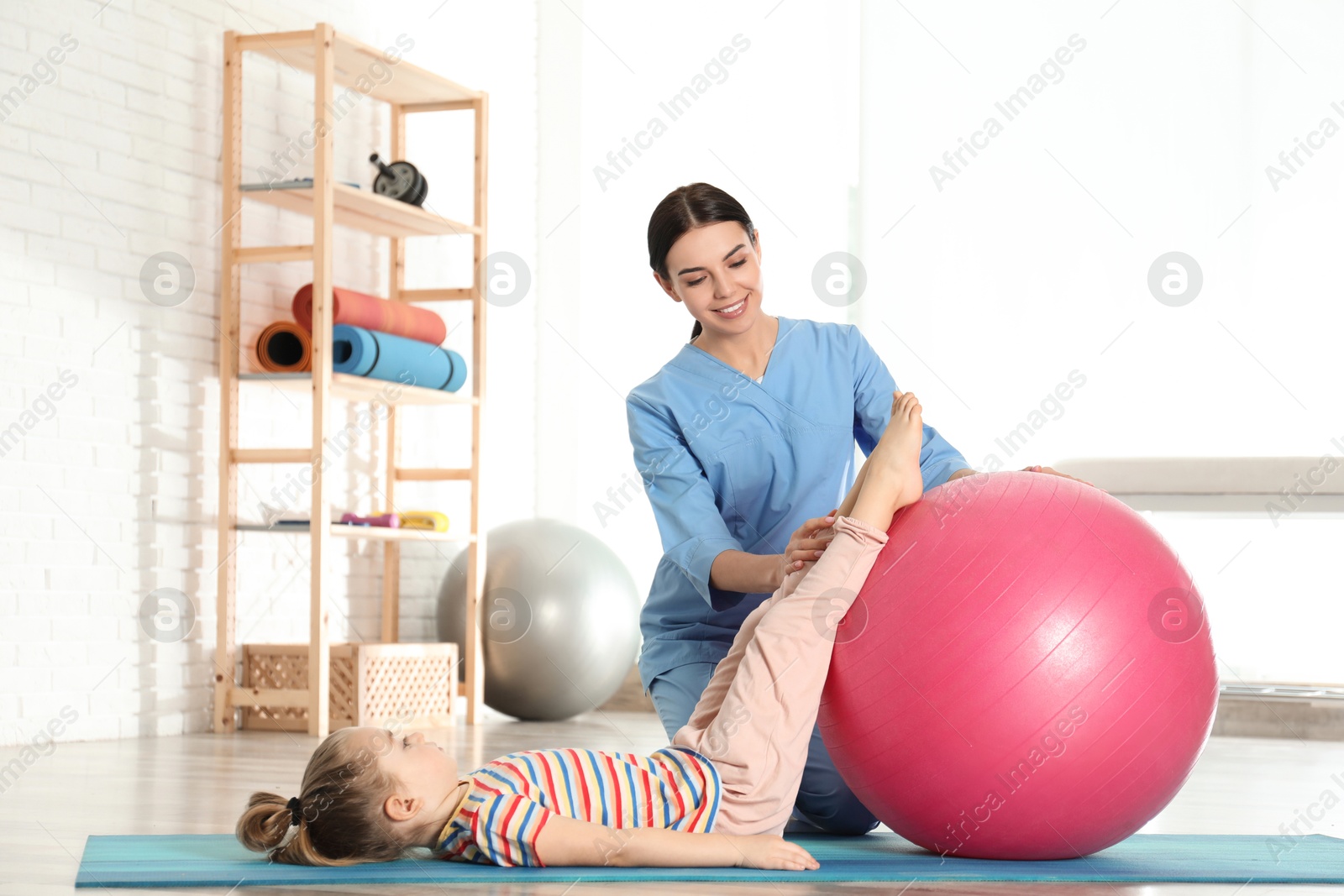 Photo of Orthopedist working with little girl in hospital gym