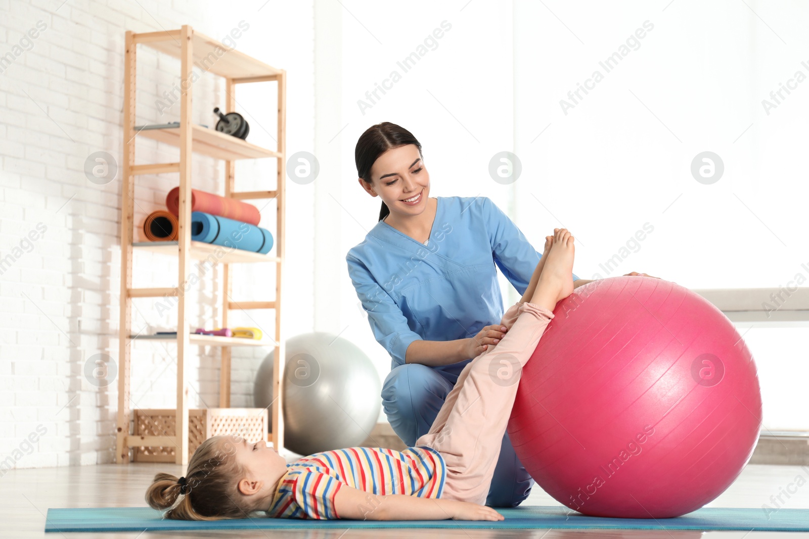 Photo of Orthopedist working with little girl in hospital gym