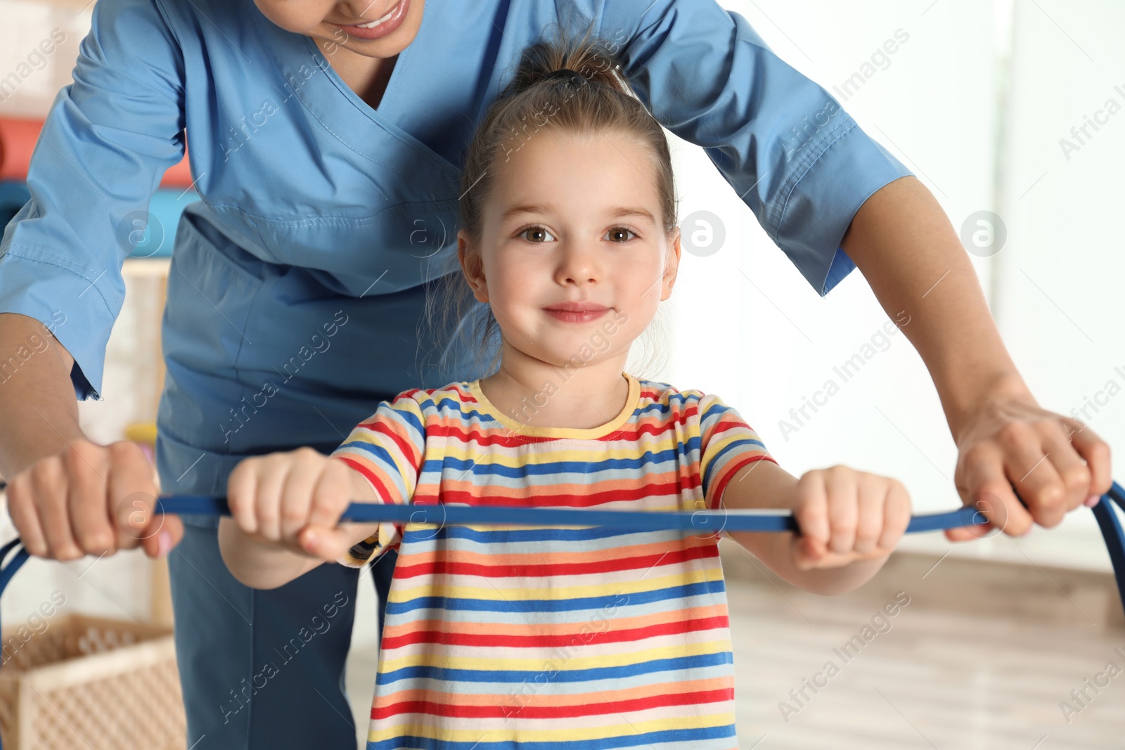 Photo of Orthopedist working with little girl in hospital gym