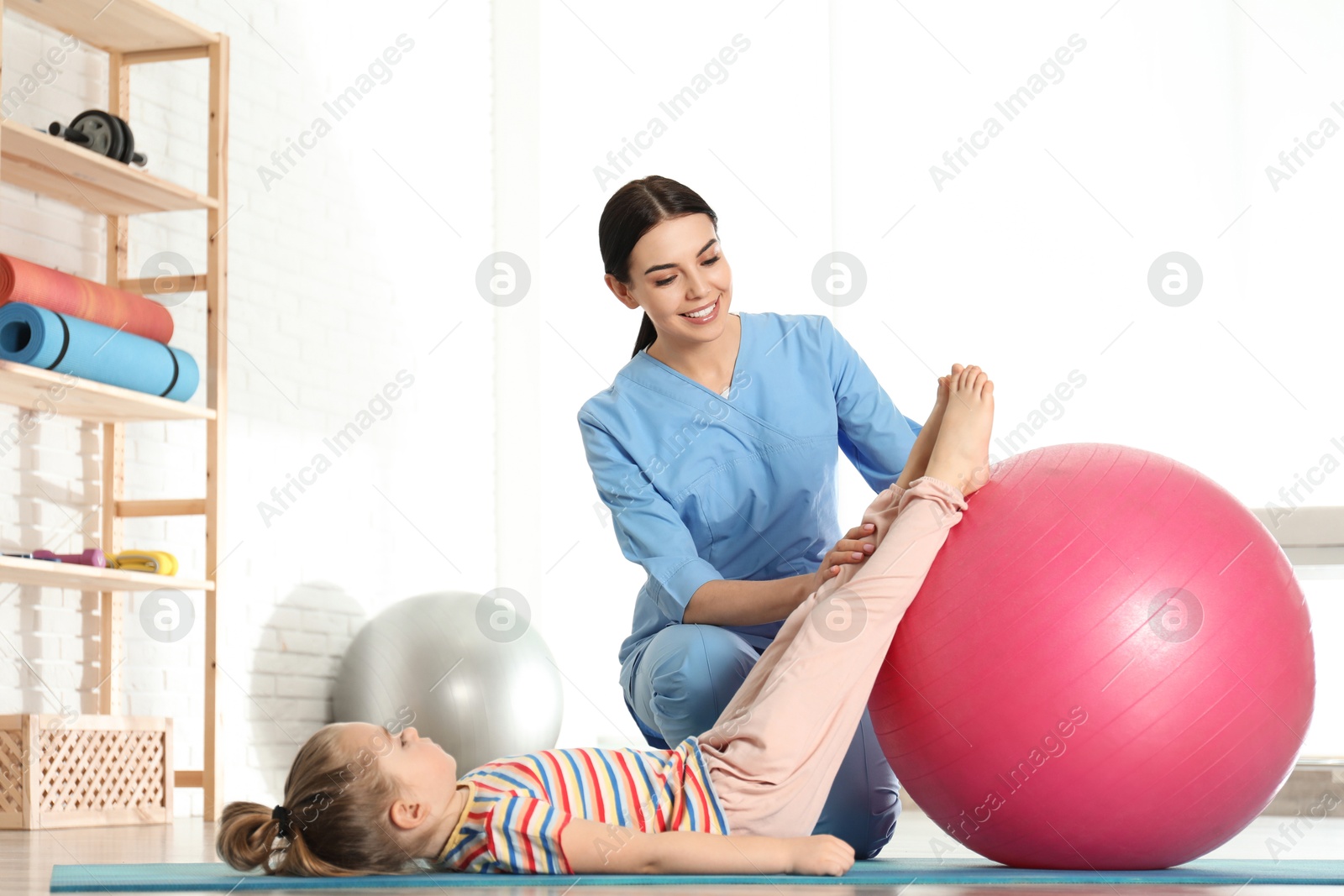 Photo of Orthopedist working with little girl in hospital gym