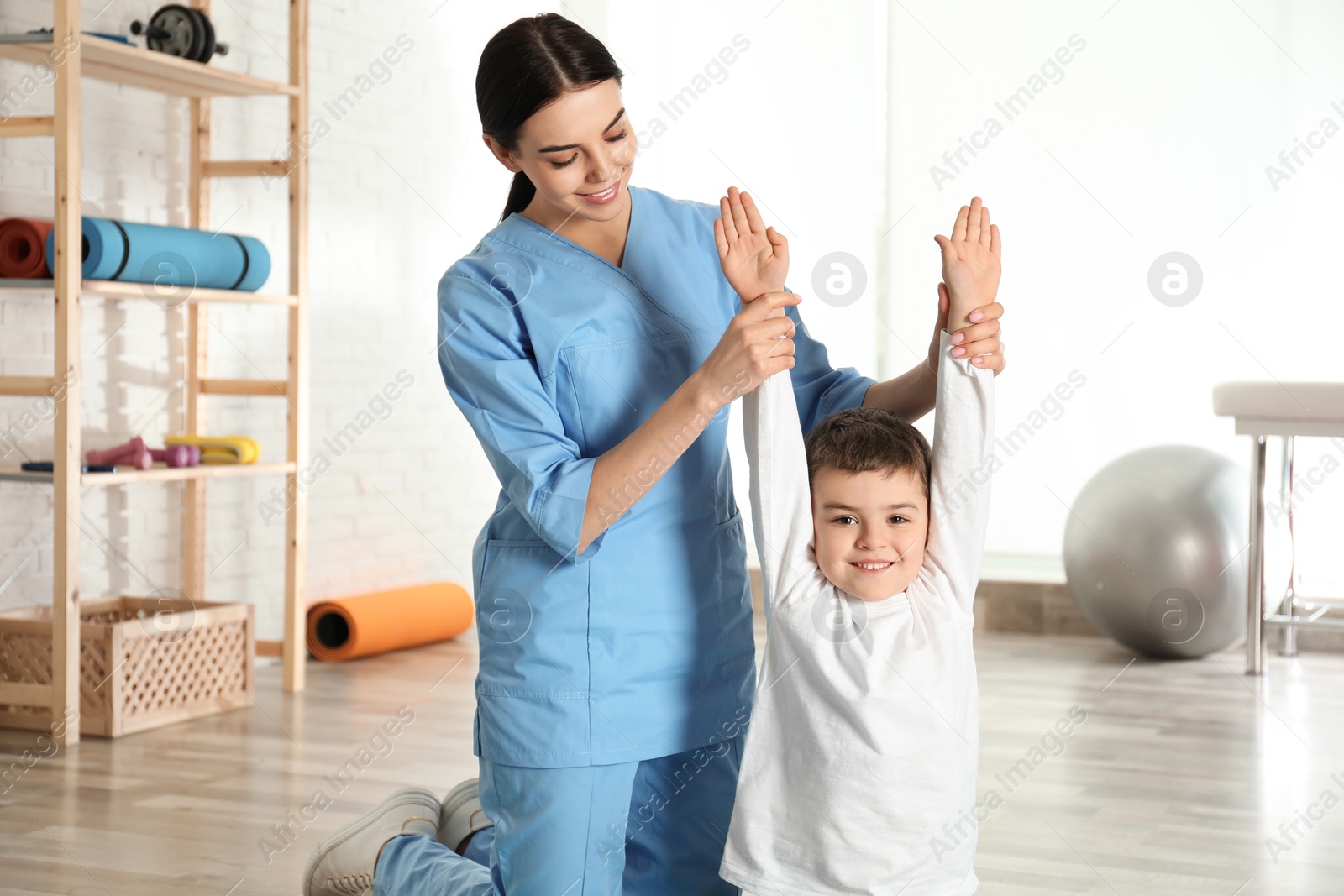 Photo of Orthopedist working with little boy in hospital gym