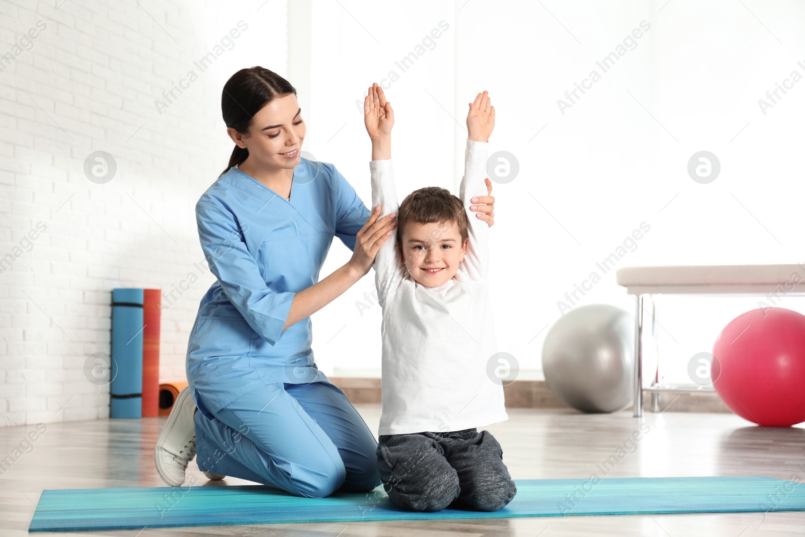 Photo of Orthopedist working with little boy in hospital gym