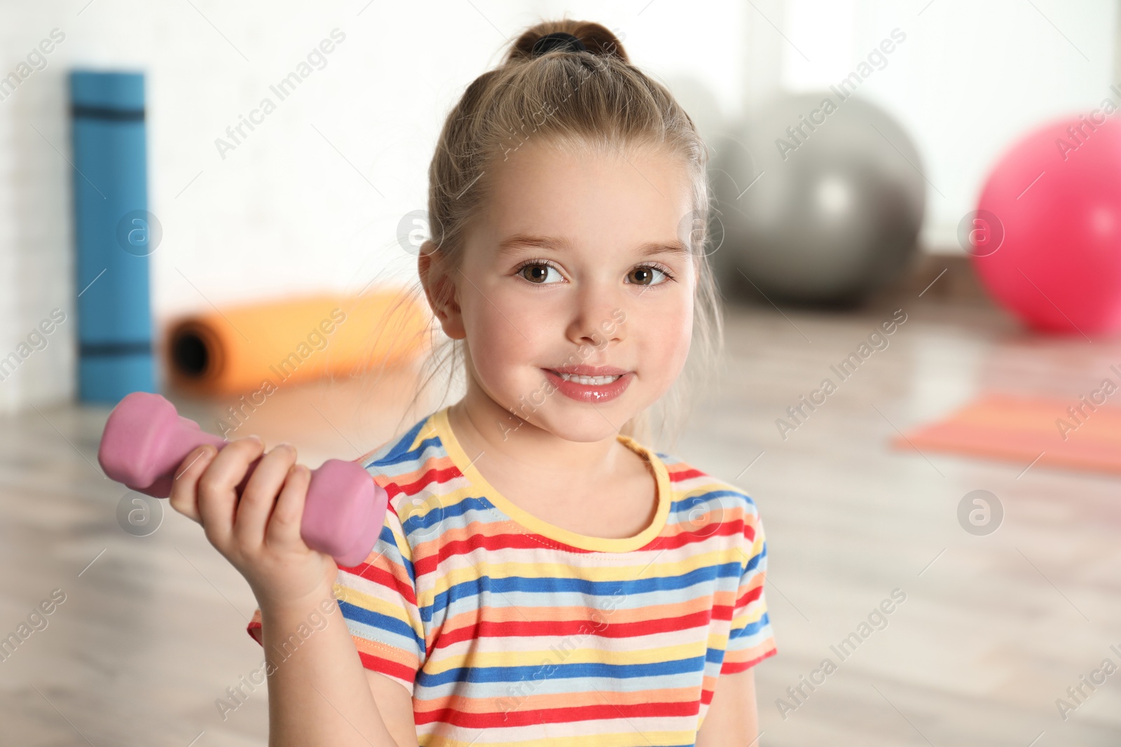 Photo of Little girl with dumbbell in hospital gym. Orthopedist's help