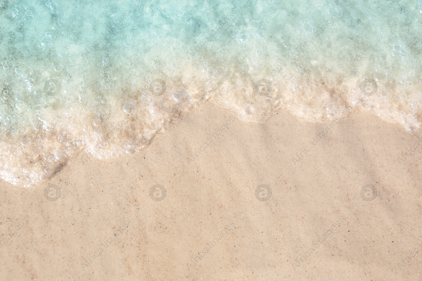 Photo of Sea waves rolling on beautiful sandy beach, top view. Summer vacation