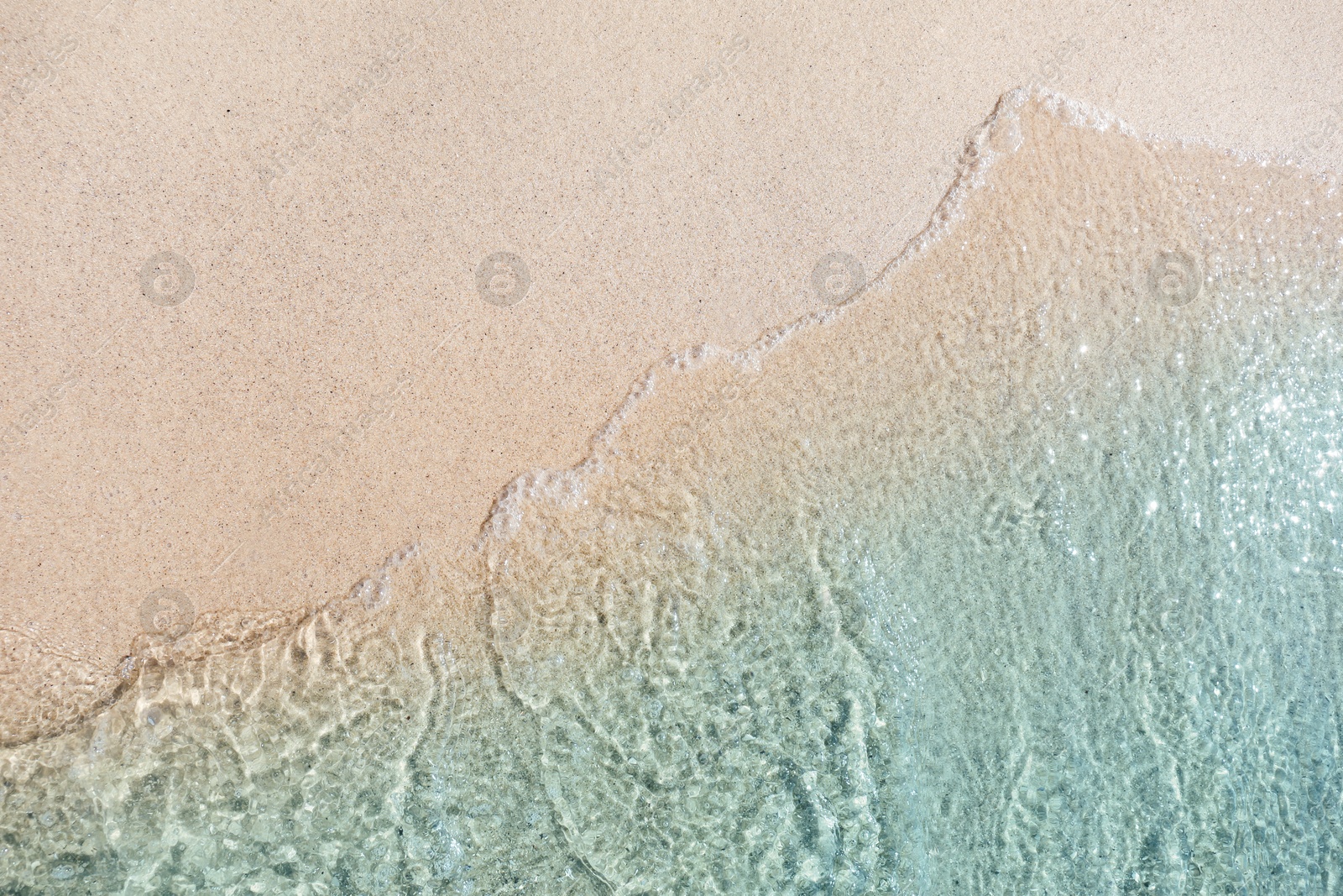 Photo of Sea waves rolling on beautiful sandy beach, top view. Summer vacation