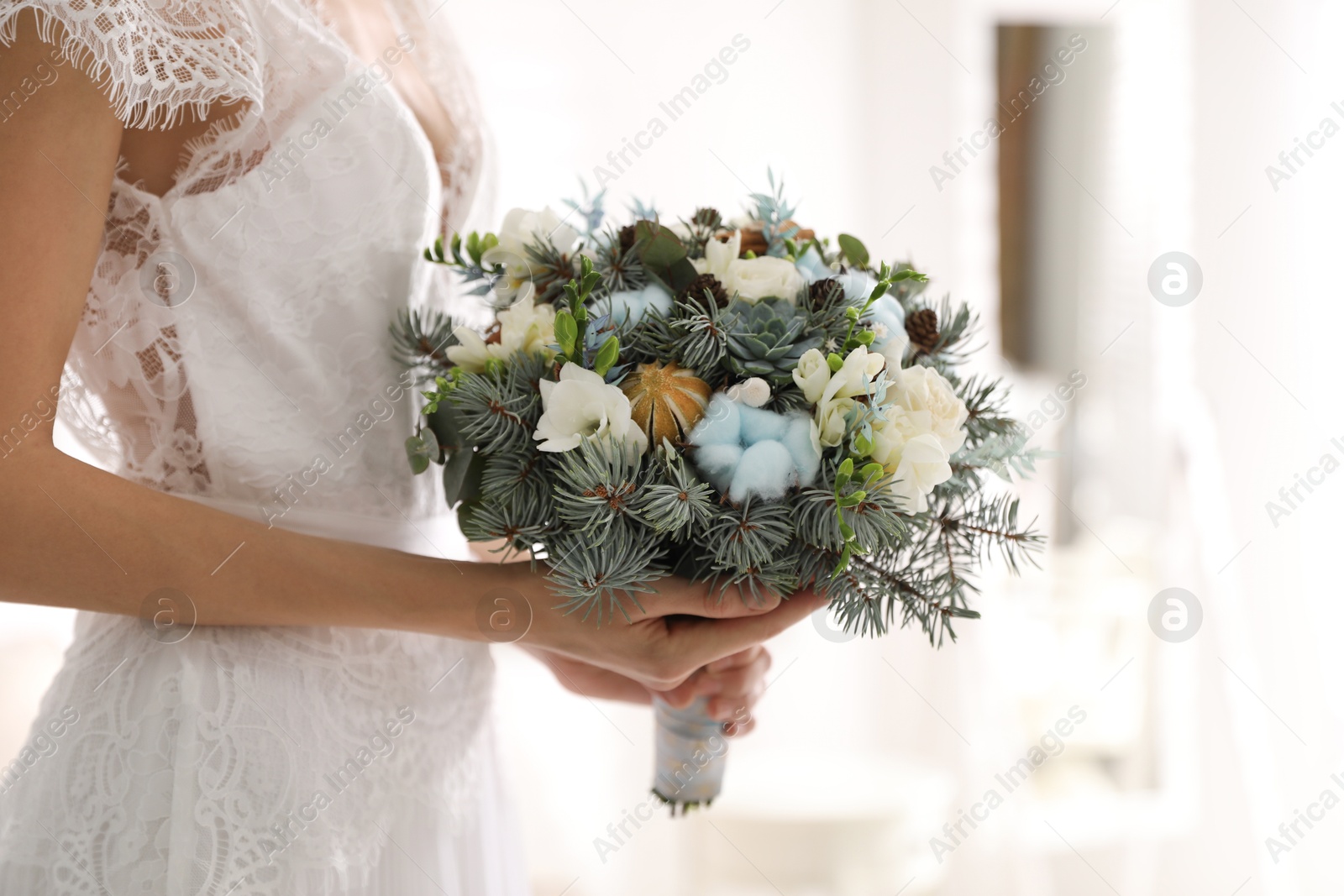 Photo of Young bride with beautiful winter wedding 
 bouquet indoors, closeup