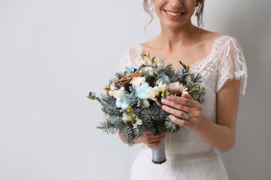 Photo of Beautiful bride with winter wedding bouquet on light grey background, closeup