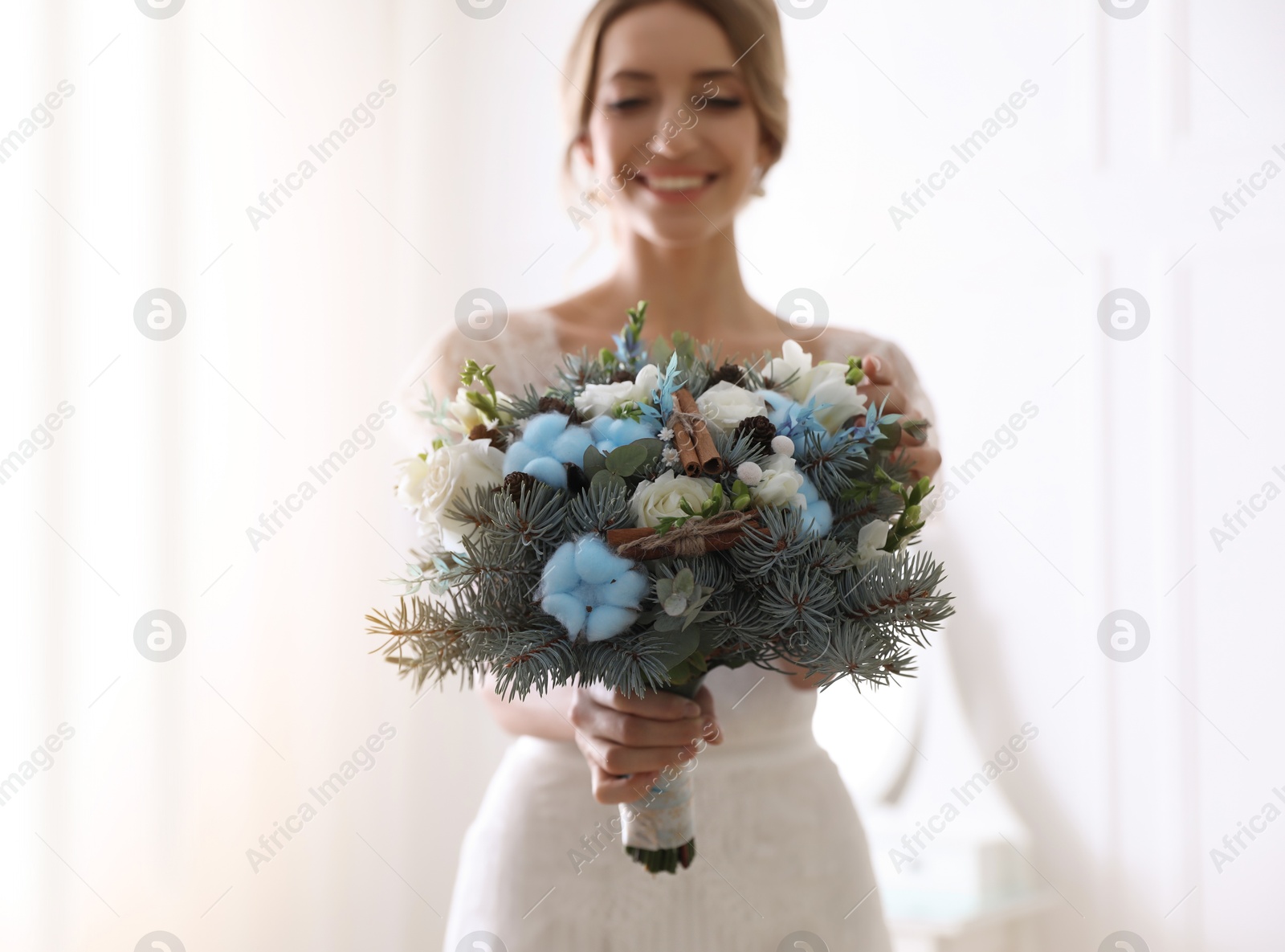 Photo of Beautiful bride with winter wedding bouquet indoors, focus on flowers