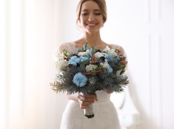 Beautiful bride with winter wedding bouquet indoors, focus on flowers