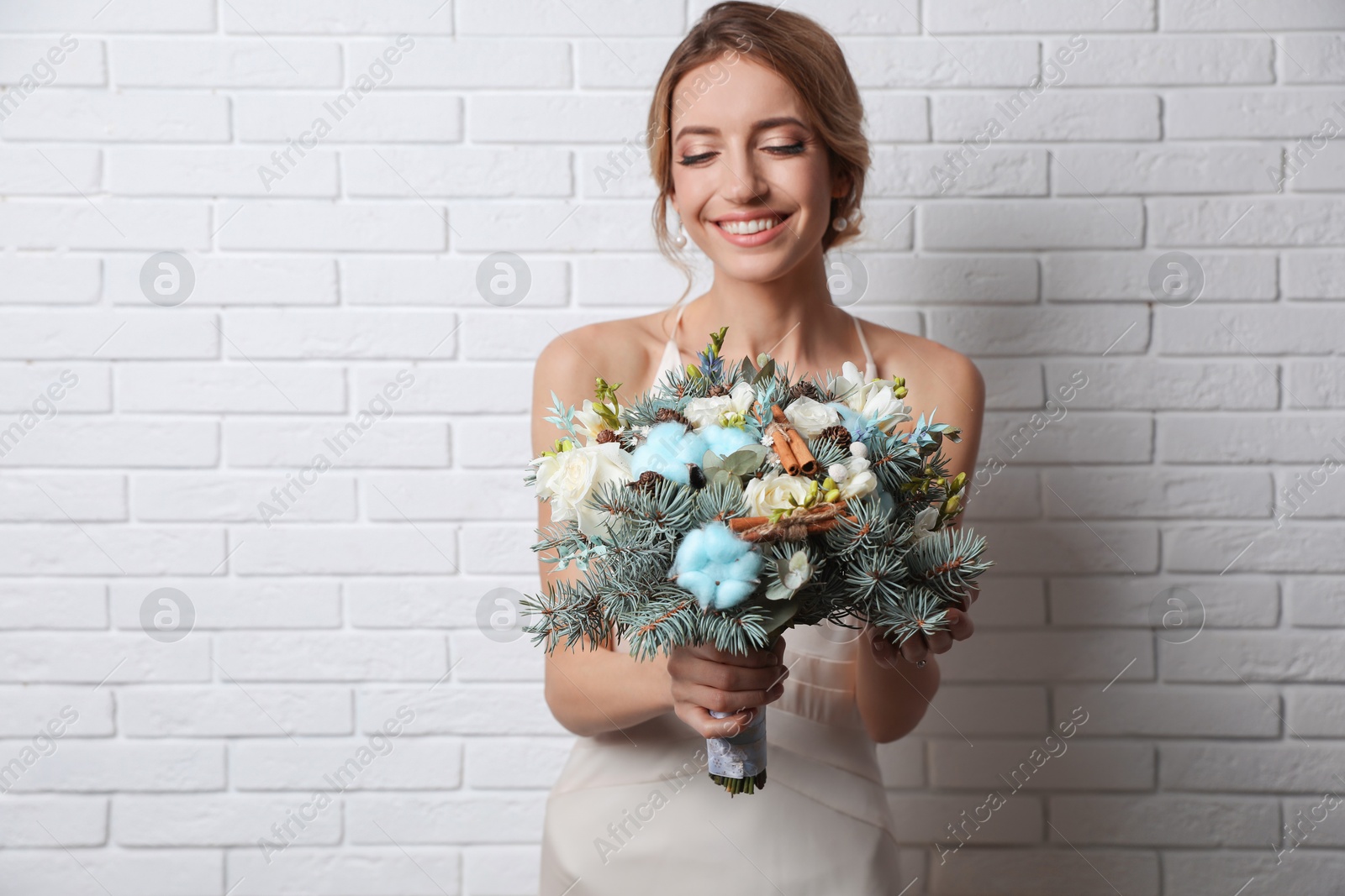 Photo of Beautiful bride with winter wedding bouquet near white brick wall