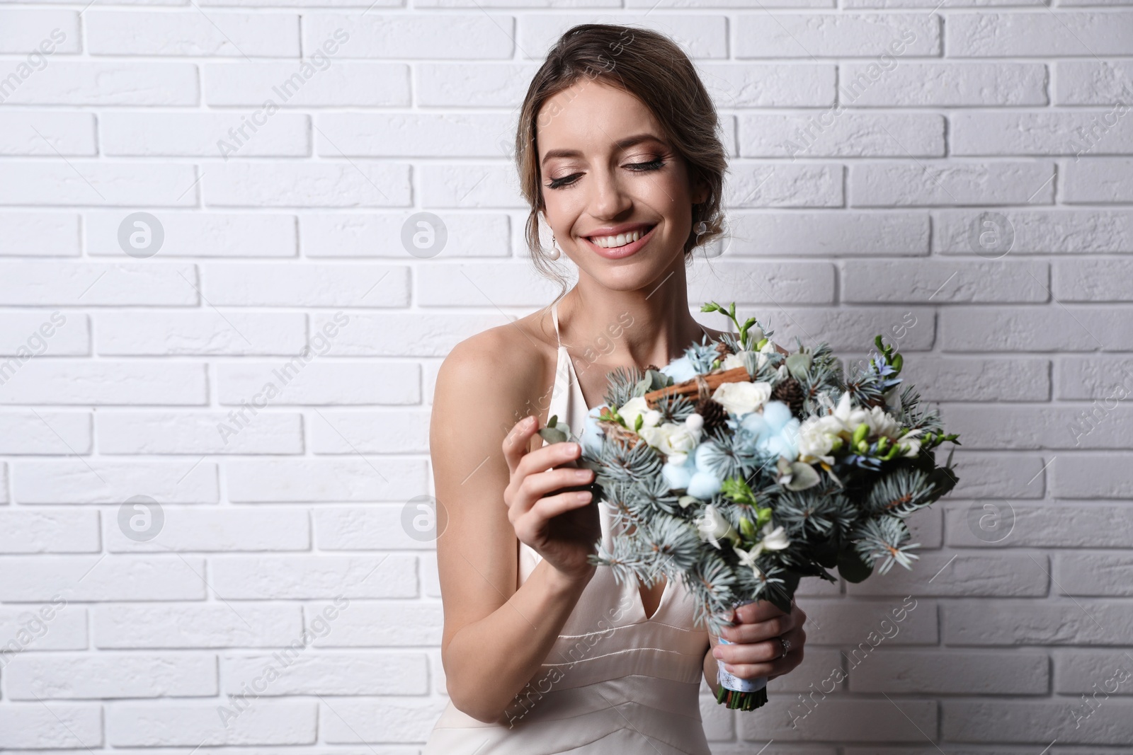 Photo of Beautiful bride with winter wedding bouquet near white brick wall