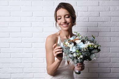 Beautiful bride with winter wedding bouquet near white brick wall