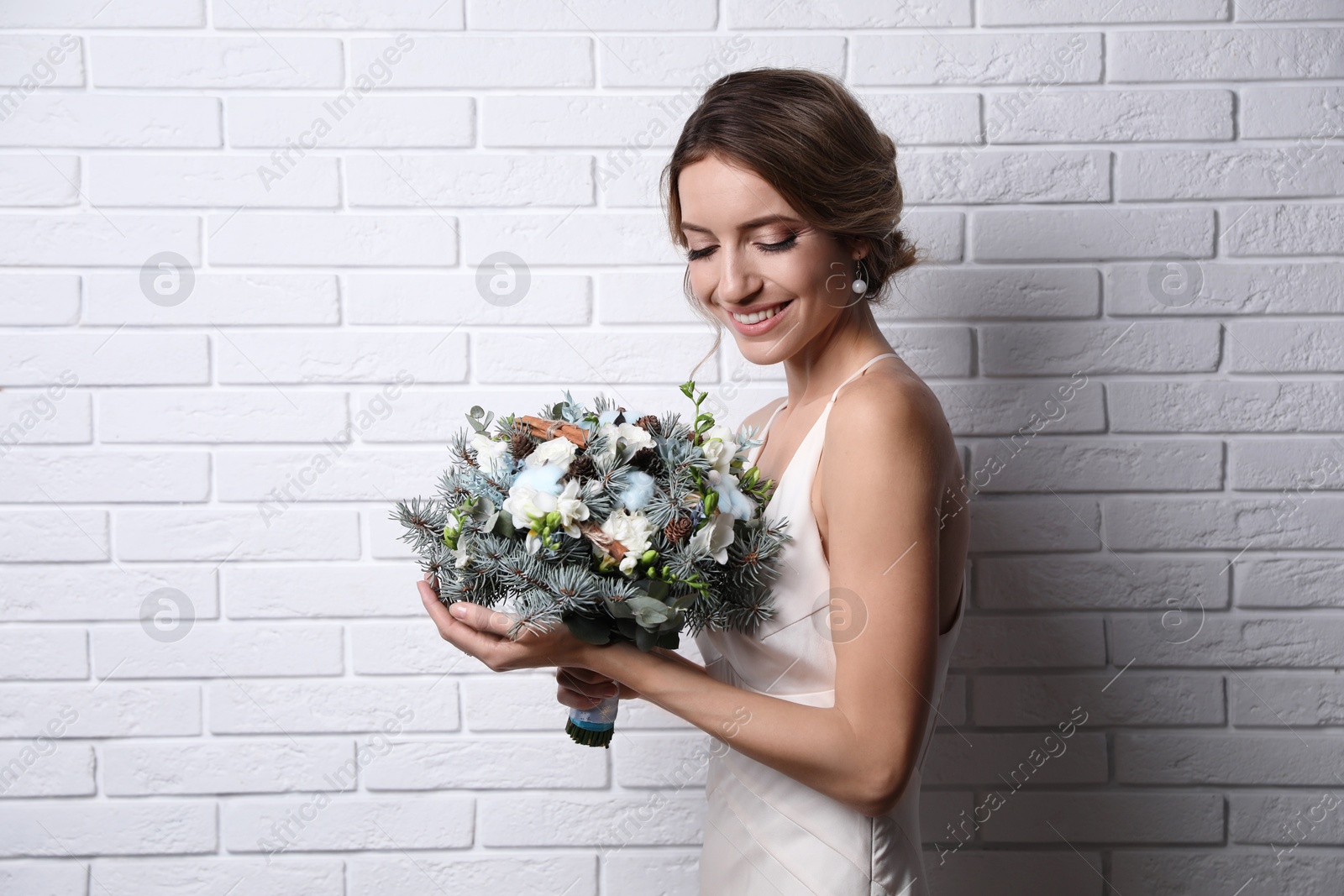 Photo of Beautiful bride with winter wedding bouquet near white brick wall