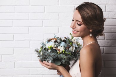 Photo of Beautiful bride with winter wedding bouquet near white brick wall