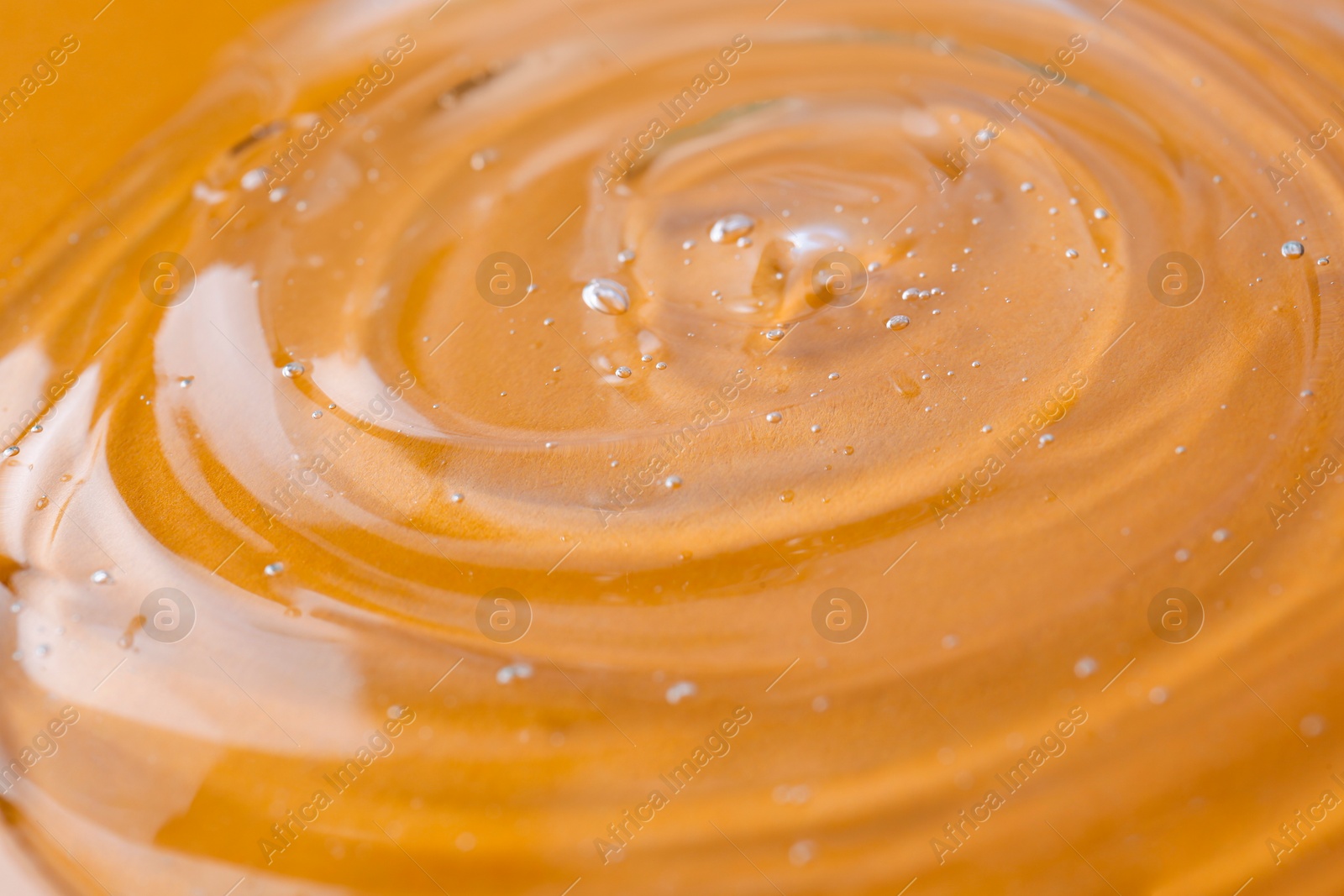 Photo of Sample of transparent shower gel on orange background, closeup