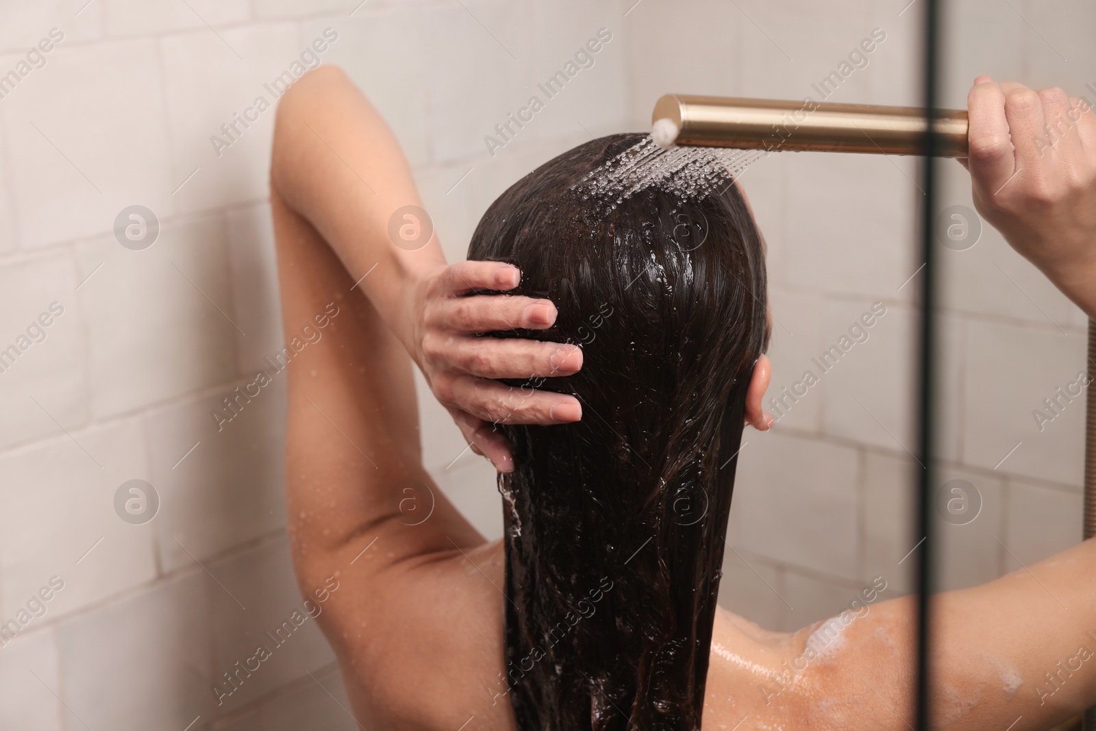 Photo of Woman washing hair while taking shower at home, back view