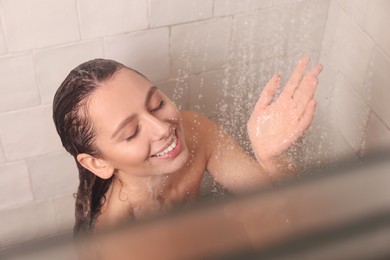Photo of Happy woman washing hair while taking shower at home, above view