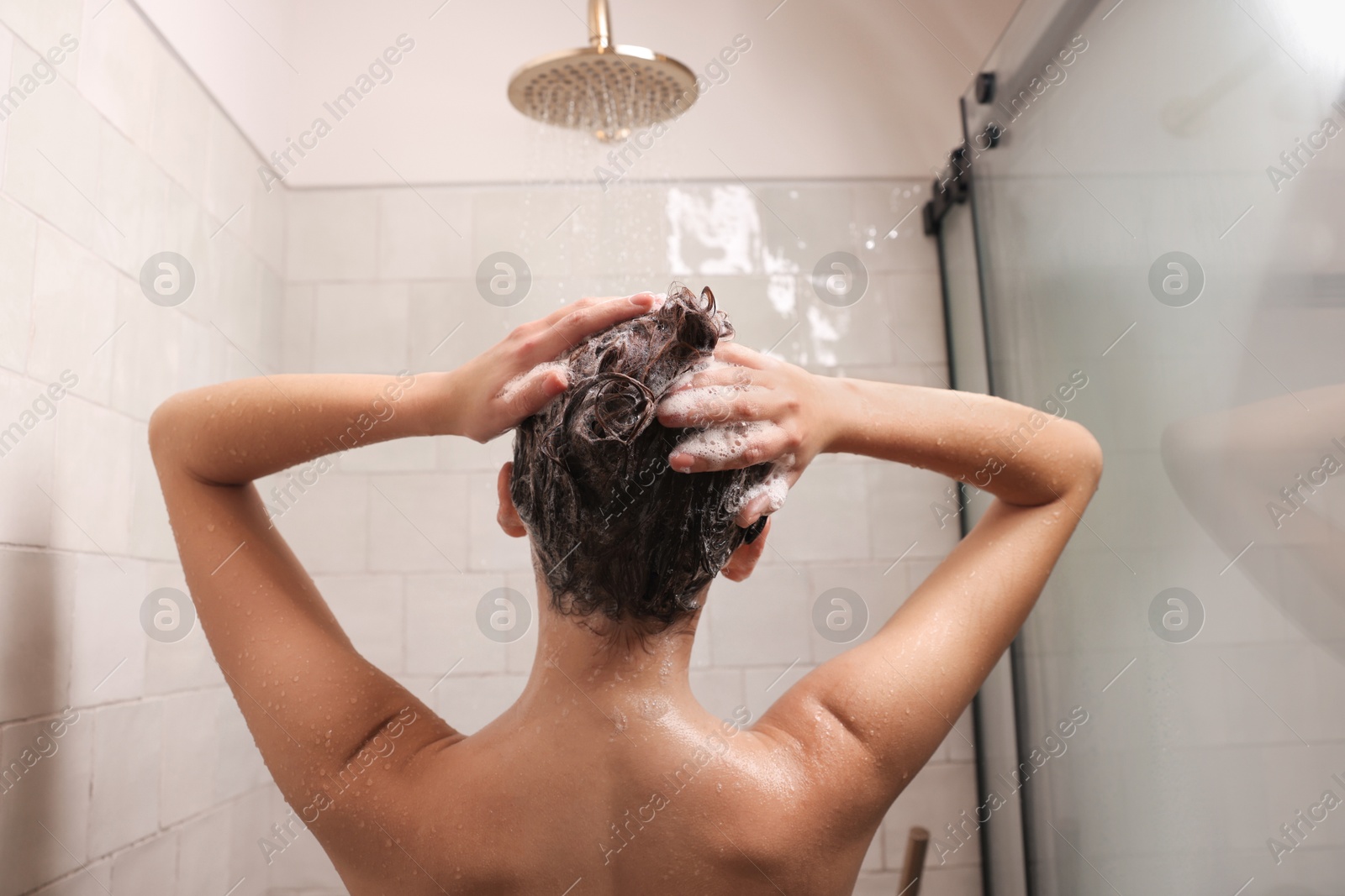 Photo of Woman washing hair while taking shower at home, back view