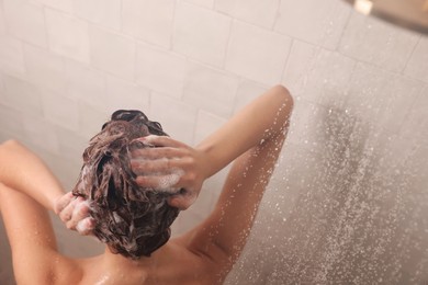 Photo of Young woman washing hair while taking shower at home, above view