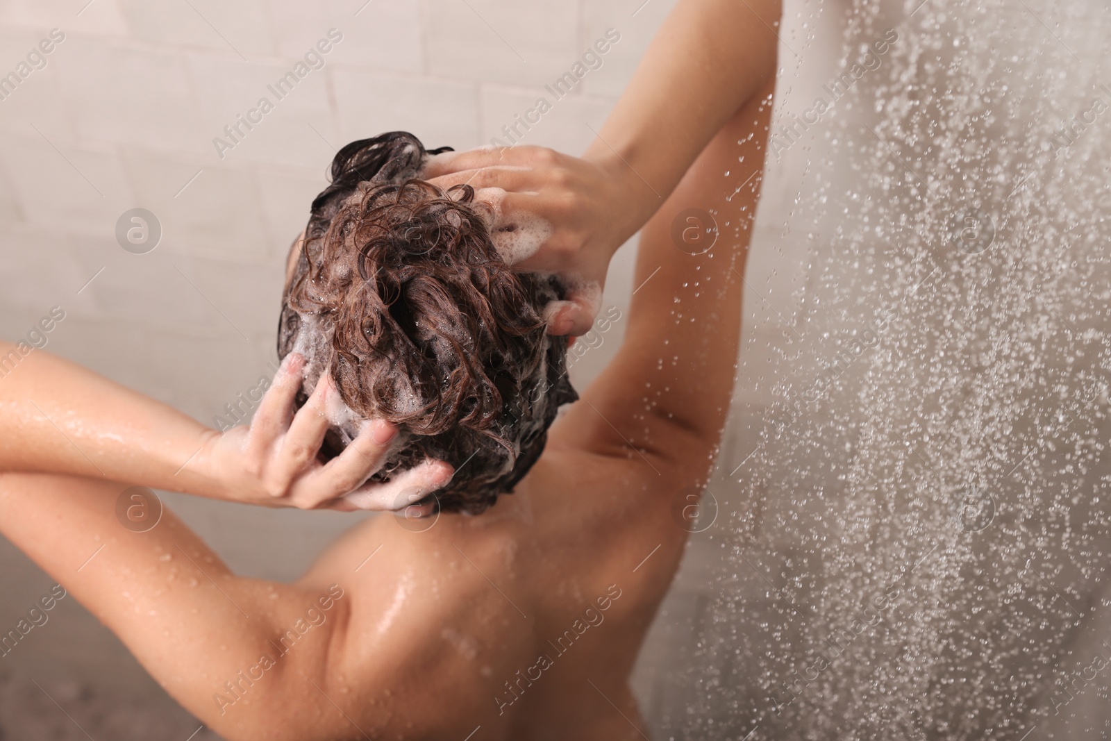 Photo of Young woman washing hair while taking shower at home, above view