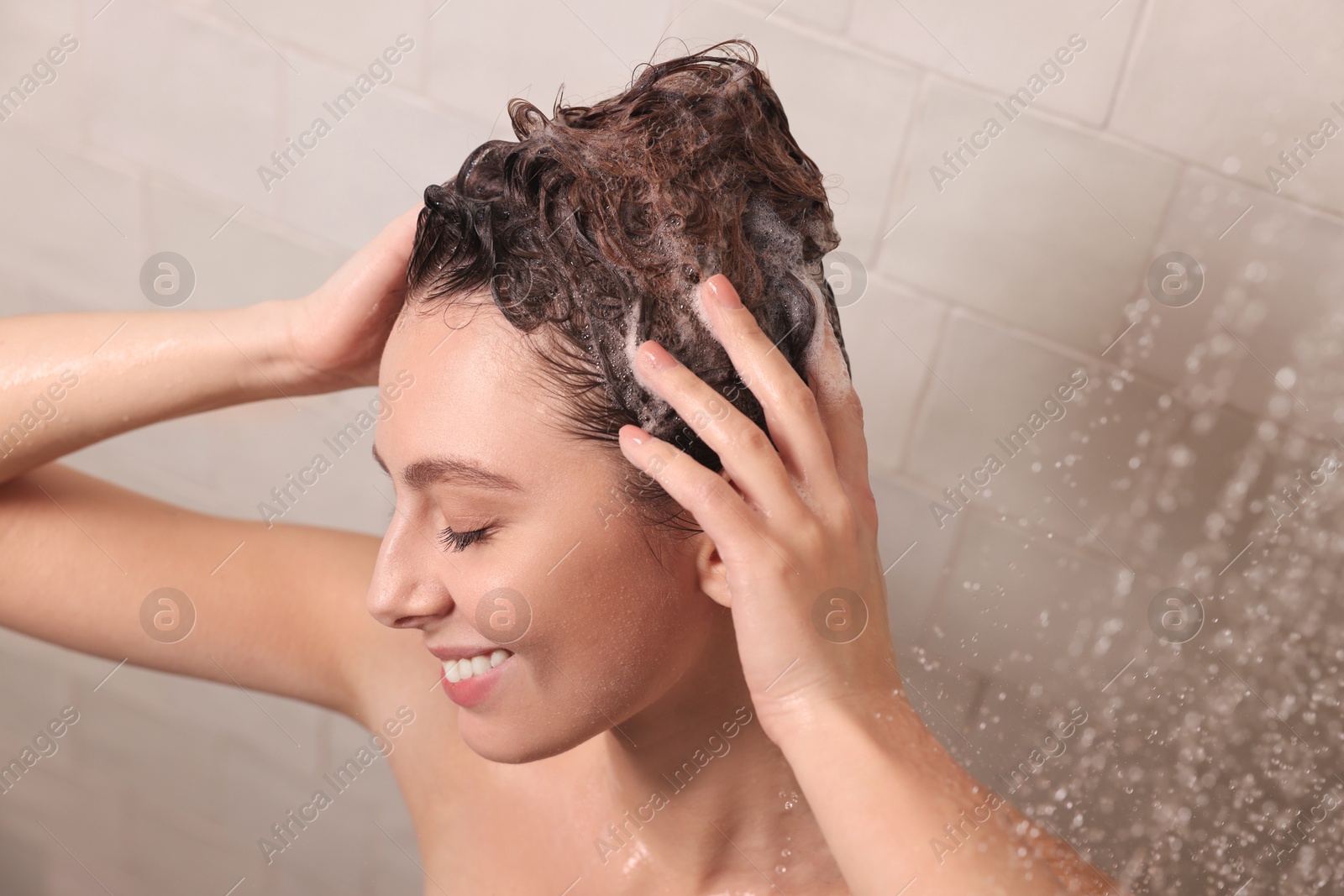 Photo of Happy woman washing hair while taking shower at home