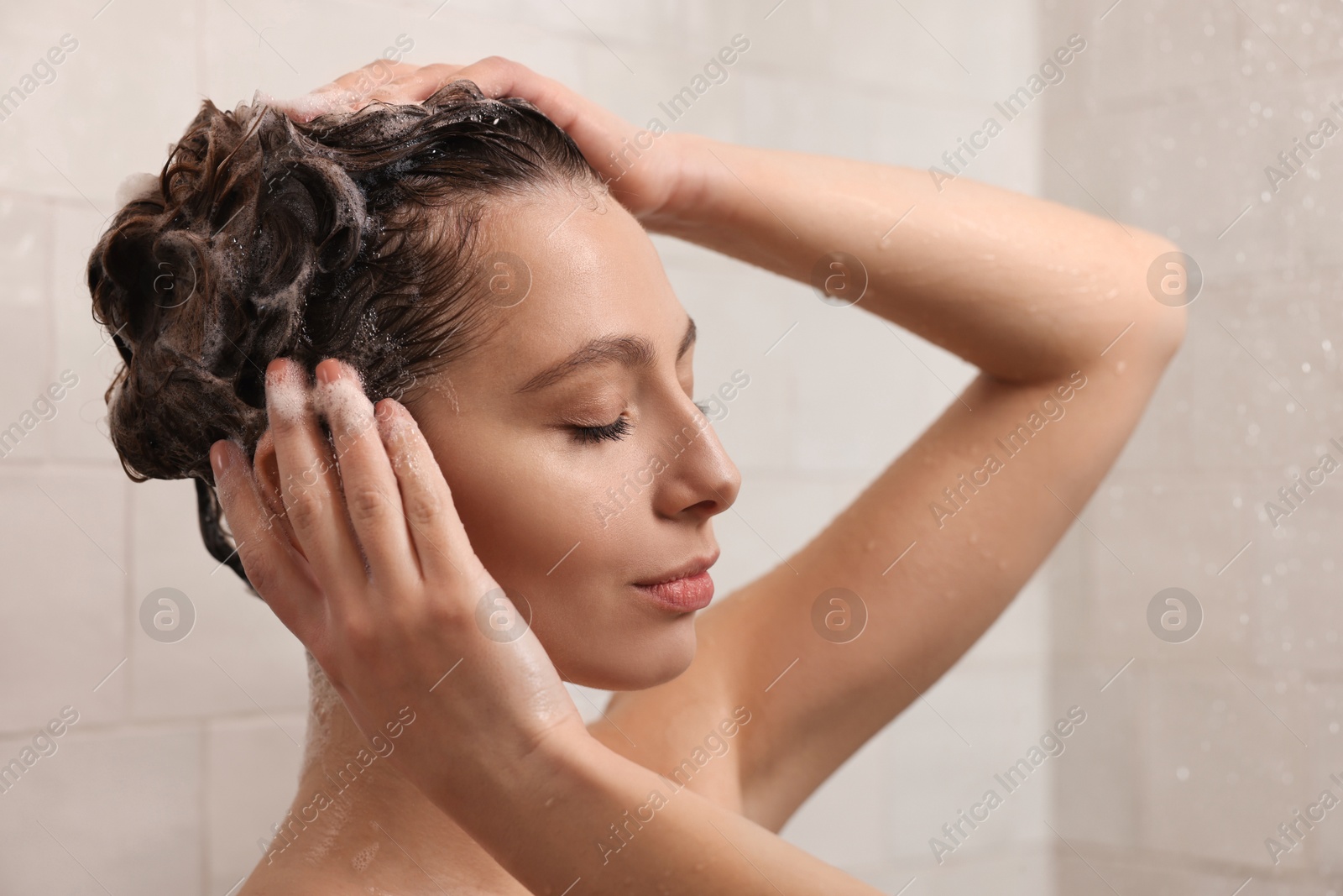 Photo of Young woman washing hair while taking shower at home