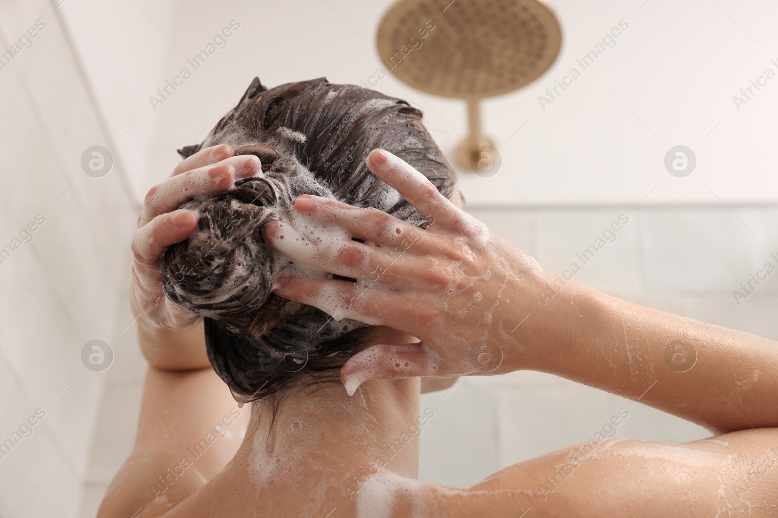 Photo of Woman washing hair while taking shower at home, back view