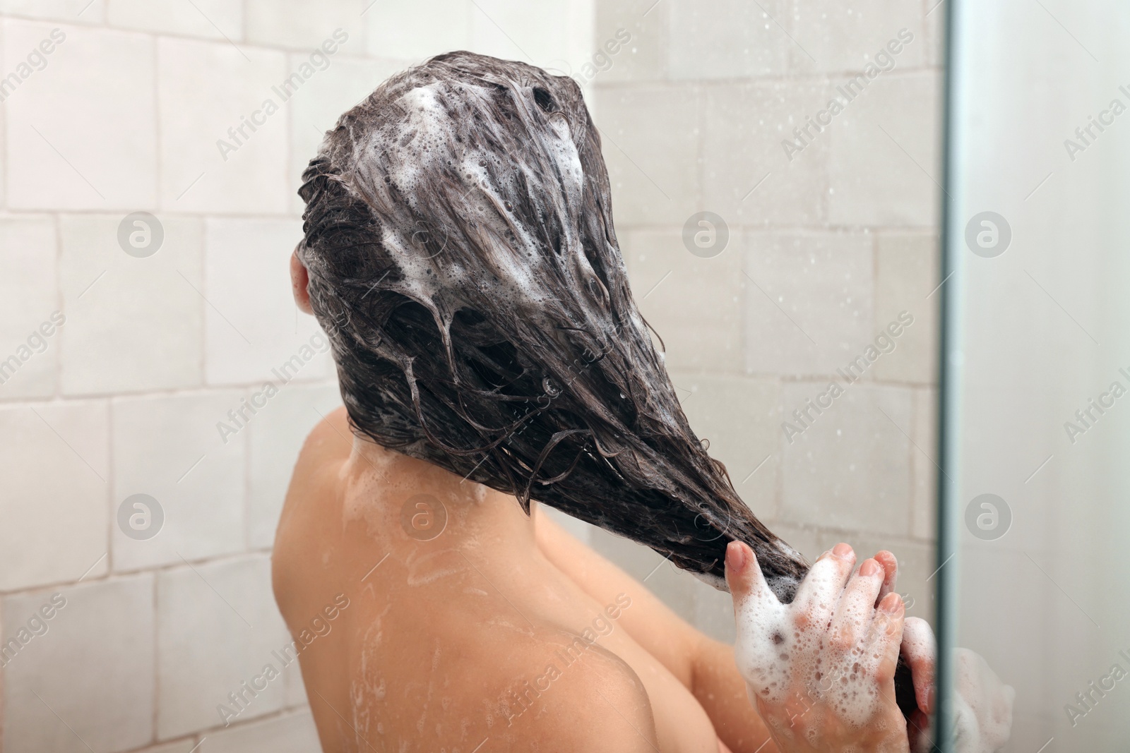 Photo of Young woman washing hair while taking shower at home